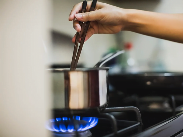 A woman is seen lighting the gas stove.