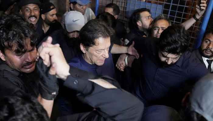 Policemen escort former prime minister Imran Khan (C) as he arrives at the high court in Islamabad on May 12, 2023.